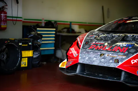 Lamborghini GT3 ferma nel box con gomme e attrezzatura attorno