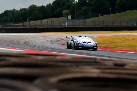 Lamborghini Huracán GT3 bianca inquadrata oltre le barriere di pneumatici