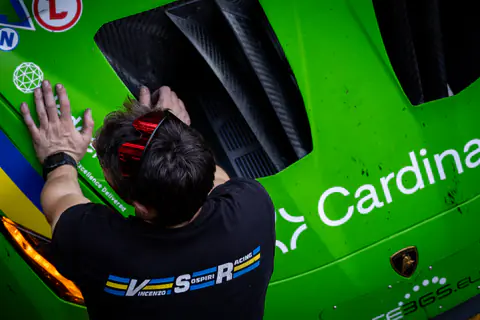 Meccanico appoggia le mani sulla carrozzeria verde di una Lamborghini da competizione