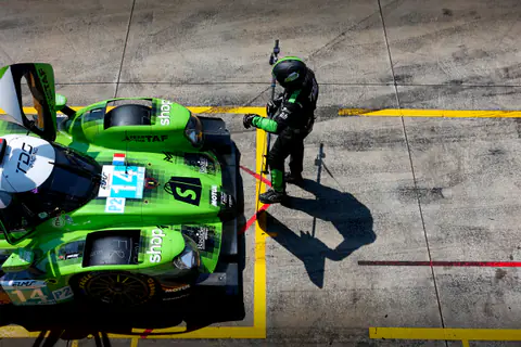 Vista dall'alto di una Lamborghini verde ferma nella piazzola box con i meccanici attorno